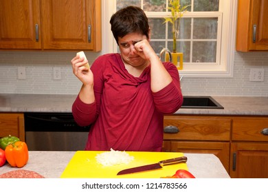 Woman Holds Onion And Rubs Tears From Her Eyes In The Kitchen 