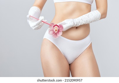 A woman holds a pink orchid in her hands and makes injections for rejuvenation. The concept of plastic surgery.