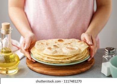 Woman holds plate with cooked mexican flatbread. Step by step recipe of homemade tortillas.