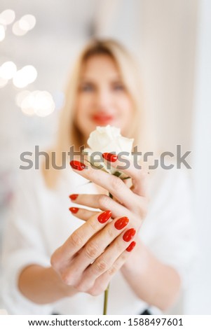Woman holds rose, focus on manicure and flower