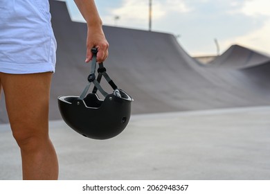 A woman holds a safety helmet after riding in an extreme park. Close-up. The skate park, rollerdrome, quarter and half pipe ramps. Extreme sport, youth urban culture for teen street activity. - Powered by Shutterstock