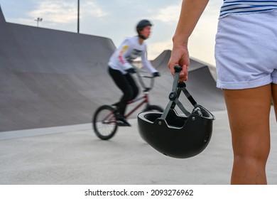 A woman holds a safety helmet after riding in an extreme park. Close-up. The skate park, rollerdrome, quarter and half pipe ramps. Extreme sport, youth urban culture for teen street activity. - Powered by Shutterstock