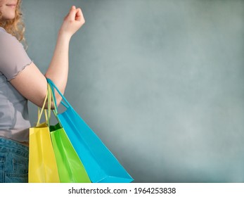 Woman  holds shopping bags in blue, green and yellow. On the right is space to put in your own text.