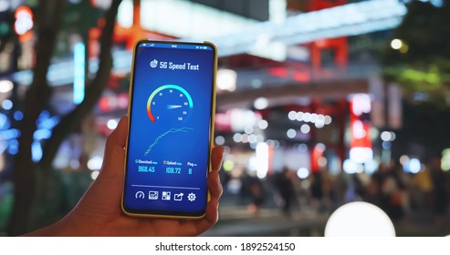 Woman Holds Smartphone With 5g Speed Test Near Department Store With Crowded People