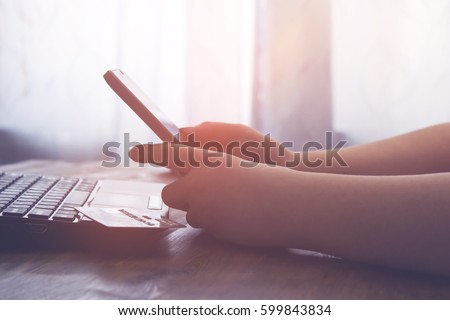 A woman holds a smartp-hone sitting at the table. vintage effect