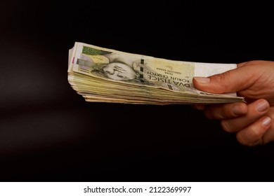 A woman holds a stack of Czech cash crowns on a black background. Much money .