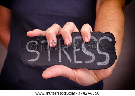 Woman holds Stress word written on black paper. Close up.