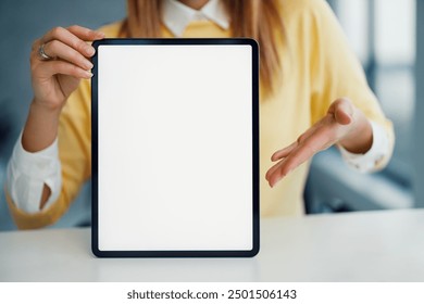 Woman holds a tablet with a blank screen while sitting in a modern office setting. Ideal for showcasing technology, digital presentations, and professional environments. - Powered by Shutterstock