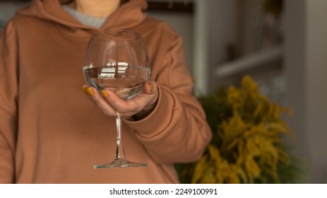 Woman holds a wine glass of clean water. The concept of dry January and sober October. Avoiding alcohol throughout the month. Healthy lifestyle. - Powered by Shutterstock