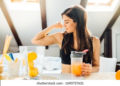 Woman at home drinking orange flavored amino acid vitamin powder.Keto supplement.After exercise liquid meal.Weight loss fitness nutrition diet.Immune system support.Organic citrus fruit drink