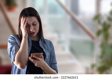 Woman at home hold a phone in hands - Shutterstock ID 2227662611