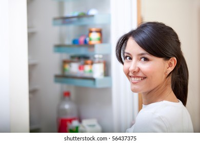 Woman At Home Looking Inside The Fridge And Smiling