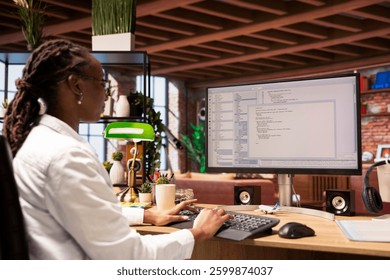 Woman in home office looking at UI on computer screen, typing and executing programming code. Coding application UI used by african american IT developer writing and testing code in modern apartment