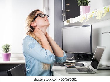 Woman In Home Office Suffering From Neck Pain Sitting At Computer Desk