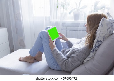 Woman At Home Relaxing Reading On The Tablet Computer With Pre-keyed Green Screen