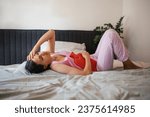 Woman at home suffering from menstrual pain. Menstrual cramps, woman warming lower abdomen with a hot water bottle, endometriosis, and diseases causing pain.