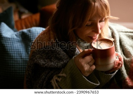 Woman At Home Wearing Winter Jumper And Blanket With Warming Hot Drink Of Coffee In Cup Or Mug