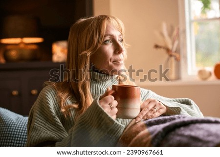 Woman At Home Wearing Winter Jumper With Warming Hot Drink Of Tea Or Coffee In Cup Or Mug
