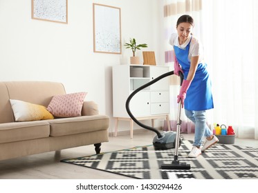 Woman hoovering carpet in living room. Cleaning service