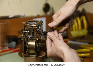 Woman horologist hands using tweezwers fixing a vintage clock mechanism on a repair workshop business with out of focus negative space. Fixing antique clocks concept. - Powered by Shutterstock