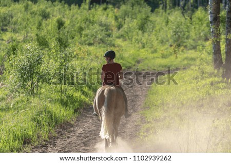 Woman horseback riding on forest path