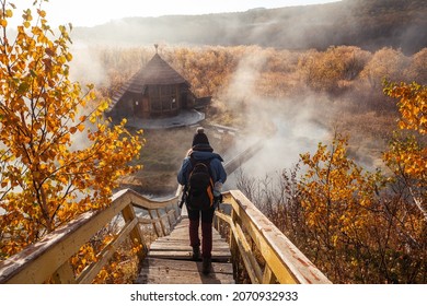 Woman At Hot Spring. First Frost, Hot Water, Beautiful Wooden House In Colourful Autumn Landscape