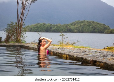 Woman in hot springs, southern Chile. Austral road. Hot waters that come out of the volcano on an island in the sea. A natural environment full of vegetation and birds. - Shutterstock ID 2052751412