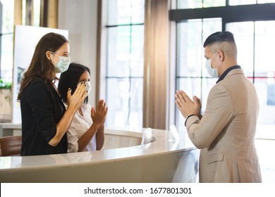 woman hotel receptionist wearing medical mask and visitor greeting thailand style instead of handshake for prevent infection coronavirus covid 19. - Powered by Shutterstock