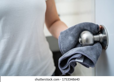 Woman House Keeper Cleaning A Dirty Stainless Door Knob In Toilet. Maid Spraying Liquid Cleaning Solution On The Dirty Door Knob Handle In Toilet And Using Micro Fabric Wipe On Door Knob Surface.