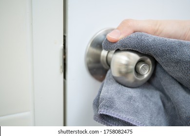 Woman House Keeper Cleaning A Dirty Stainless Door Knob In Toilet. Maid Spraying Liquid Cleaning Solution On The Dirty Door Knob Handle In Toilet And Using Micro Fabric Wipe On Door Knob Surface.