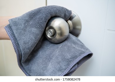 Woman House Keeper Cleaning A Dirty Stainless Door Knob In Toilet. Maid Spraying Liquid Cleaning Solution On The Dirty Door Knob Handle In Toilet And Using Micro Fabric Wipe On Door Knob Surface.