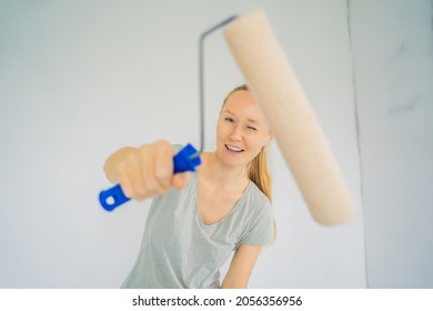 Woman House Painter Worker Painting And Priming Wall With Painting Roller. DIY