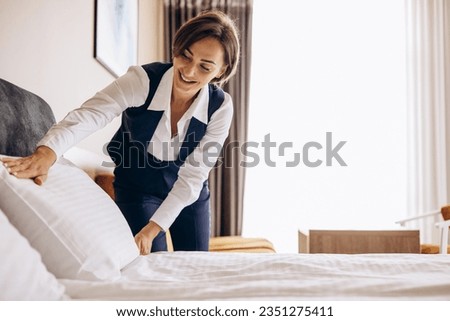 Woman housekeeper preparing bed cloths and pillows in the hotel room