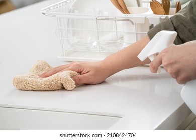 Woman housewife is doing the spring cleaning at home kitchen with using rag, spraying bottle cleaner to wipe the counter table surface.