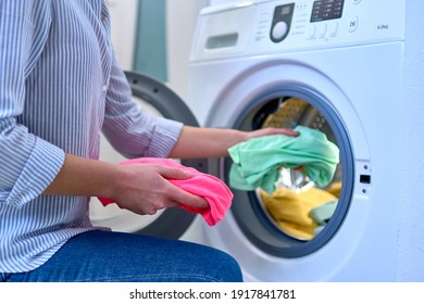 Woman housewife loads washing machine with dirty colored clothes at laundry day - Powered by Shutterstock