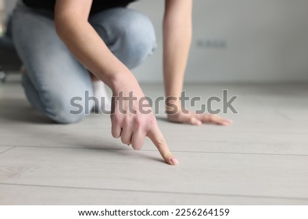 Woman housewife pointing finger at dirt on floor with laminate closeup. Quality cleaning of apartments and offices concept