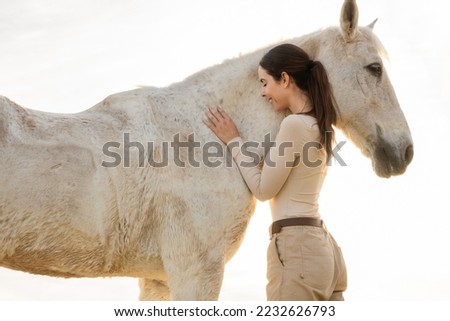 Woman hugging horse against light.