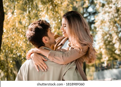 woman hugging and looking at boyfriend in autumnal park