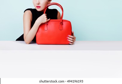 Woman Hugging The Red Bad Purse Isolated On Light Blue Background. Copyspace On The Wall And White Table. 