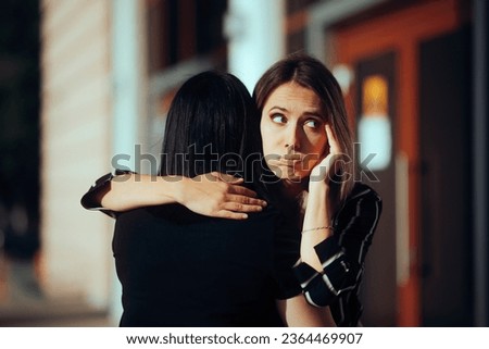 
Woman Hugs Fake Friend Making Faces Behind her Back 
Backstabbing toxic girlfriend embracing someone with bad intentions 
