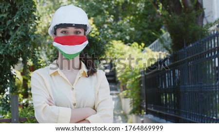 Woman with Hungary flag mask. Woman  wearing a protective mask and helmet. Under the chin, protective mask with the Hungary flag. Her mask is on her chin.