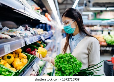 Woman With Hygienic Mask Buying In Supermarket Grocery Store For Fresh Greens,shopping During The Pandemic.Natural Source Of Vitamins And Minerals.Plant Based Diet.Covid-19 Quarantine Preparation