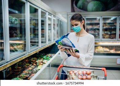 Woman With Hygienic Mask Shopping For Supplies.CPandemic Quarantine Preparation.hoosing Nonperishable Food Essentials From Store Shelves.Budget Buying At A Supply Store.Food Supplies Shortage.