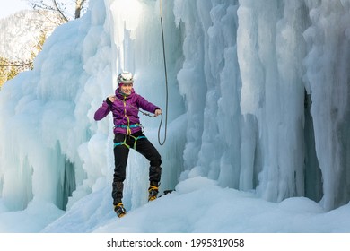 Woman Ice Climber Tying A Rope To His Harness, Preparing For A Climb