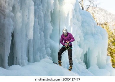 Woman Ice Climber Tying A Rope To His Harness, Preparing For A Climb