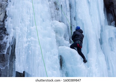 Woman Ice Climbing On A Frozen Waterfall In Alberta, Canada