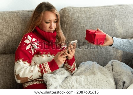 A woman ignores the Christmas gift. Mobile addiction concept