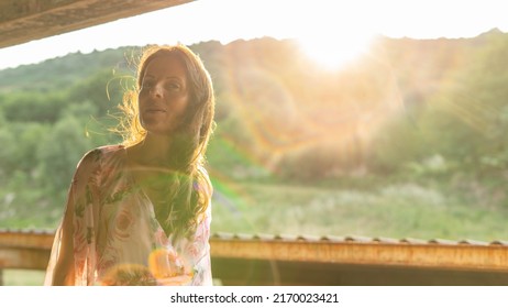 Woman Illuminated By The Last Rays Of Sun And A Gentle Wind Shows Pleasant Expression