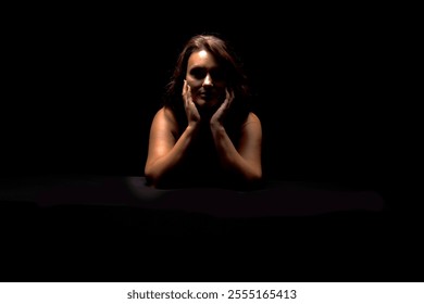 Woman illuminated in dramatic low-key lighting against a dark background. - Powered by Shutterstock