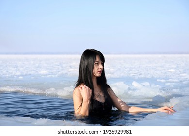 Woman immersing in icy water on winter day. Baptism ritual